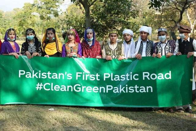 Community holding a Pakistan's First Plastic Road banner